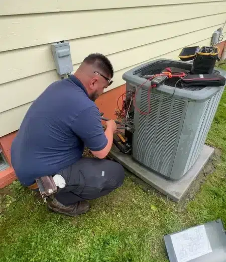 Technician repairing AC unit outside of residential home in Akron.